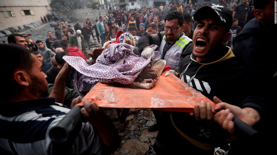 Palestinians carry a dead girl, found under the rubble of a destroyed building following Israeli airstrikes in Khan Younis, in Gaza, on December 7.
