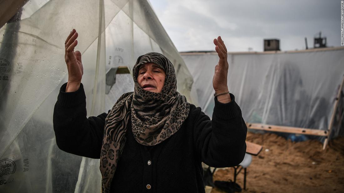 A Palestinian woman reacts as she walks past makeshift tents during a rainy day at a UN relief agency logistics base in Rafah, Gaza, on December 13.