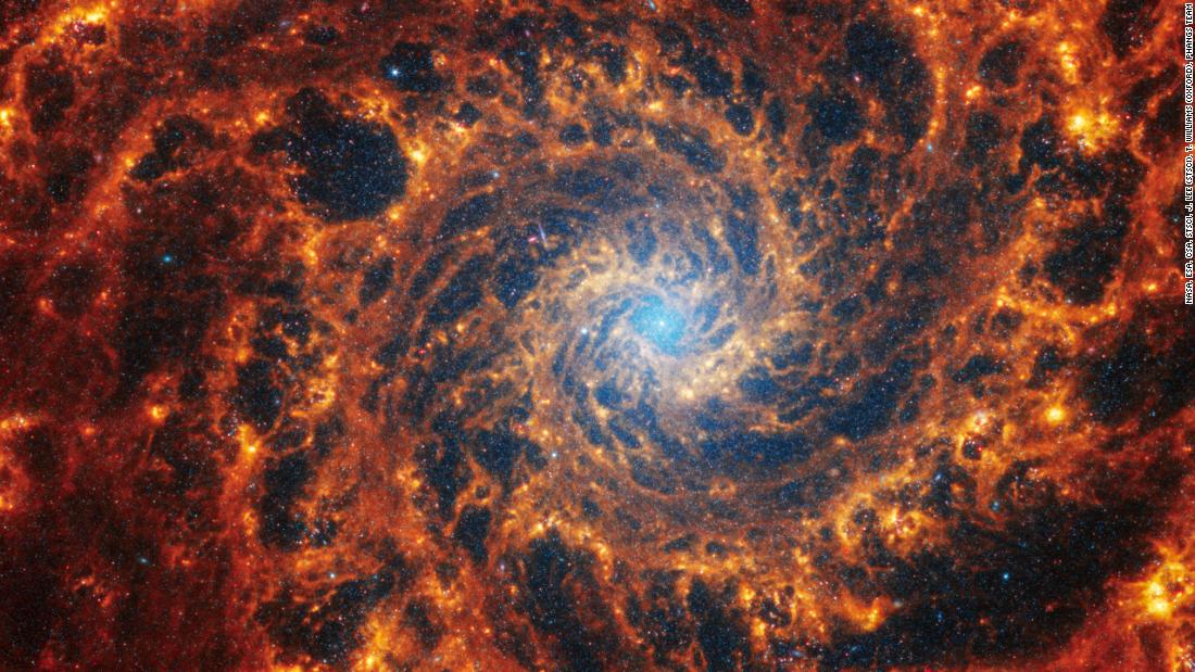 This Webb image shows a densely populated spiral galaxy anchored by a central region that has a light blue haze, known NGC 628. It&#39;s 32 million light-years away in the constellation Pisces.