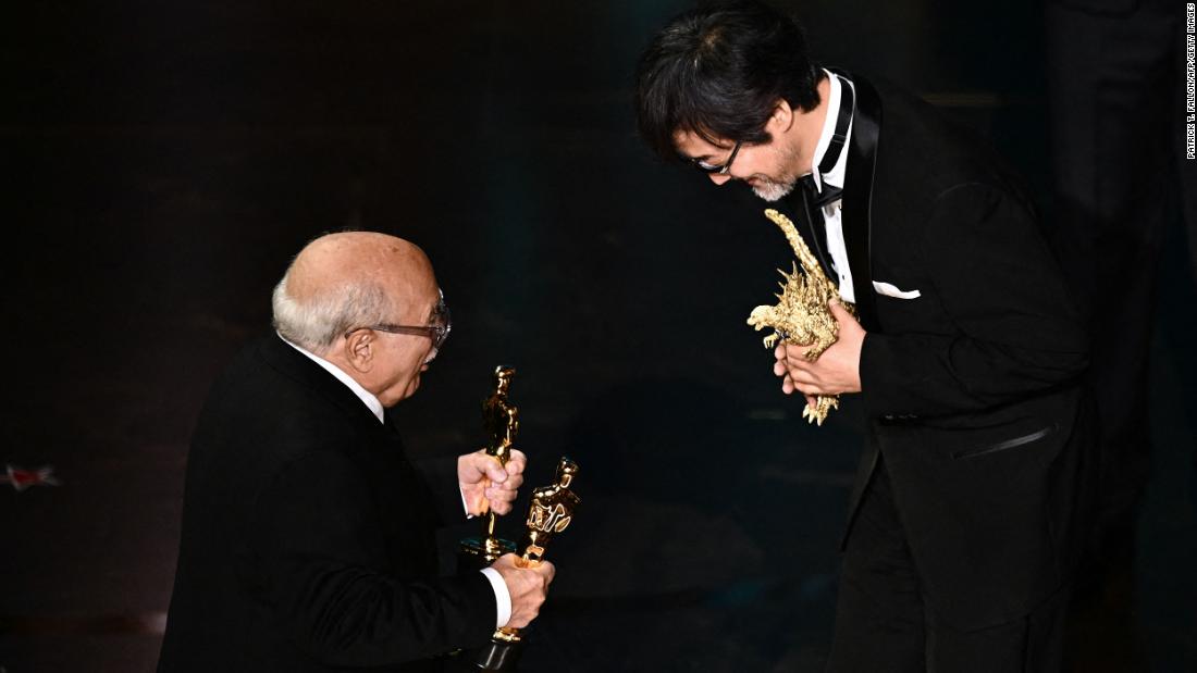 Danny DeVito, left, presents the Oscar for best visual effects to Takashi Yamazaki and &quot;Godzilla Minus One.&quot;