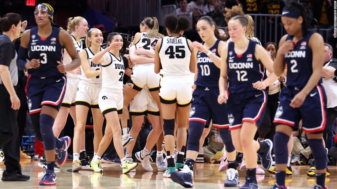 The Hawkeyes celebrate as the Huskies walk off the court after the game.