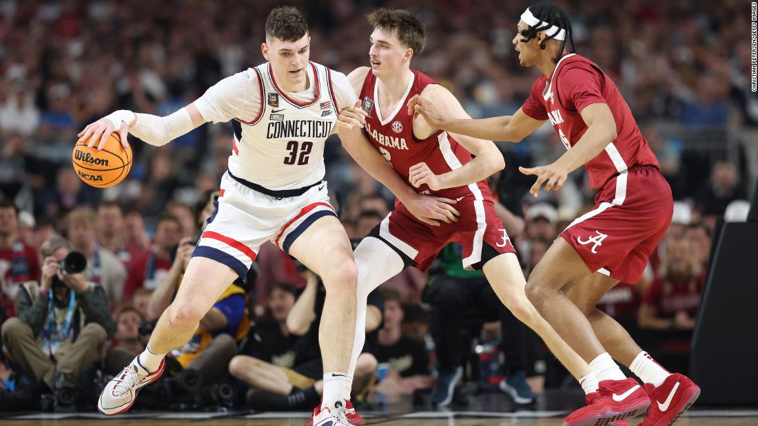 Clingan dribbles the ball under pressure from the Crimson Tide.