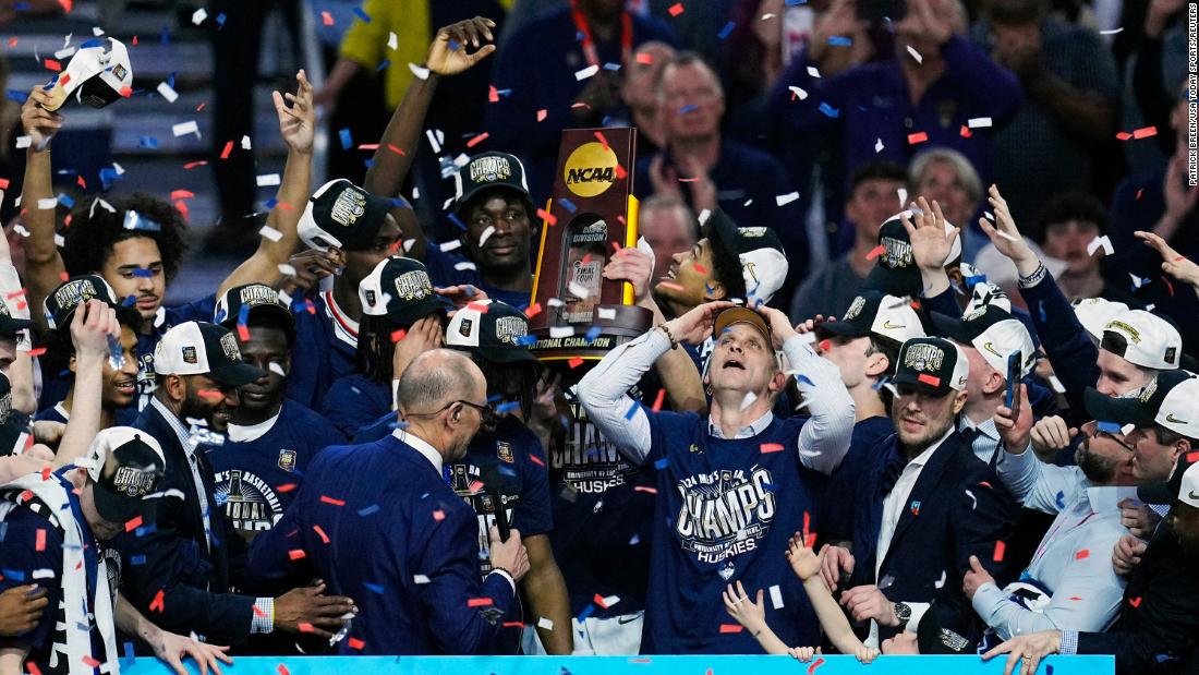 Confetti falls as the Huskies hoist the trophy while celebrating their national championship win.