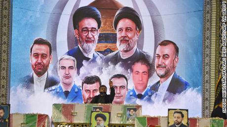CORRECTION / An Iranian man reads a prayer over the coffin of late president Ebrahim Raisi, backdropped by a mural of those who were killed with him in a helicopter crash,  during a funeral ceremony at the Imam Reza shrine, in the city of Mashhad, on May 23, 2024. Raisi and seven members of his entourage, including foreign minister Hossein Amir-Abdollahian, were killed in a helicopter crash on a fog-shrouded mountainside in Iran on May 19. (Photo by Sadegh NIKGOSTAR / FARS NEWS AGENCY / AFP) / &quot;The erroneous mention[s] appearing in the metadata of this photo by Sadegh NIKGOSTAR has been modified in AFP systems in the following manner: [Pray over the coffins] instead of [..carry the coffin]. Please immediately remove the erroneous mention[s] from all your online services and delete it (them) from your servers. If you have been authorized by AFP to distribute it (them) to third parties, please ensure that the same actions are carried out by them. Failure to promptly comply with these instructions will entail liability on your part for any continued or post notification usage. Therefore we thank you very much for all your attention and prompt action. We are sorry for the inconvenience this notification may cause and remain at your disposal for any further information you may require.&quot; (Photo by SADEGH NIKGOSTAR/FARS NEWS AGENCY/AFP via Getty Images)